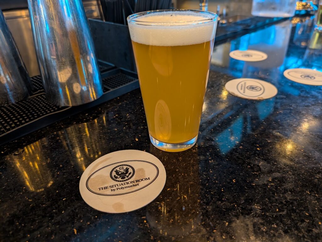 Image of a pint of pale beer, plus a series of coasters on a bar.