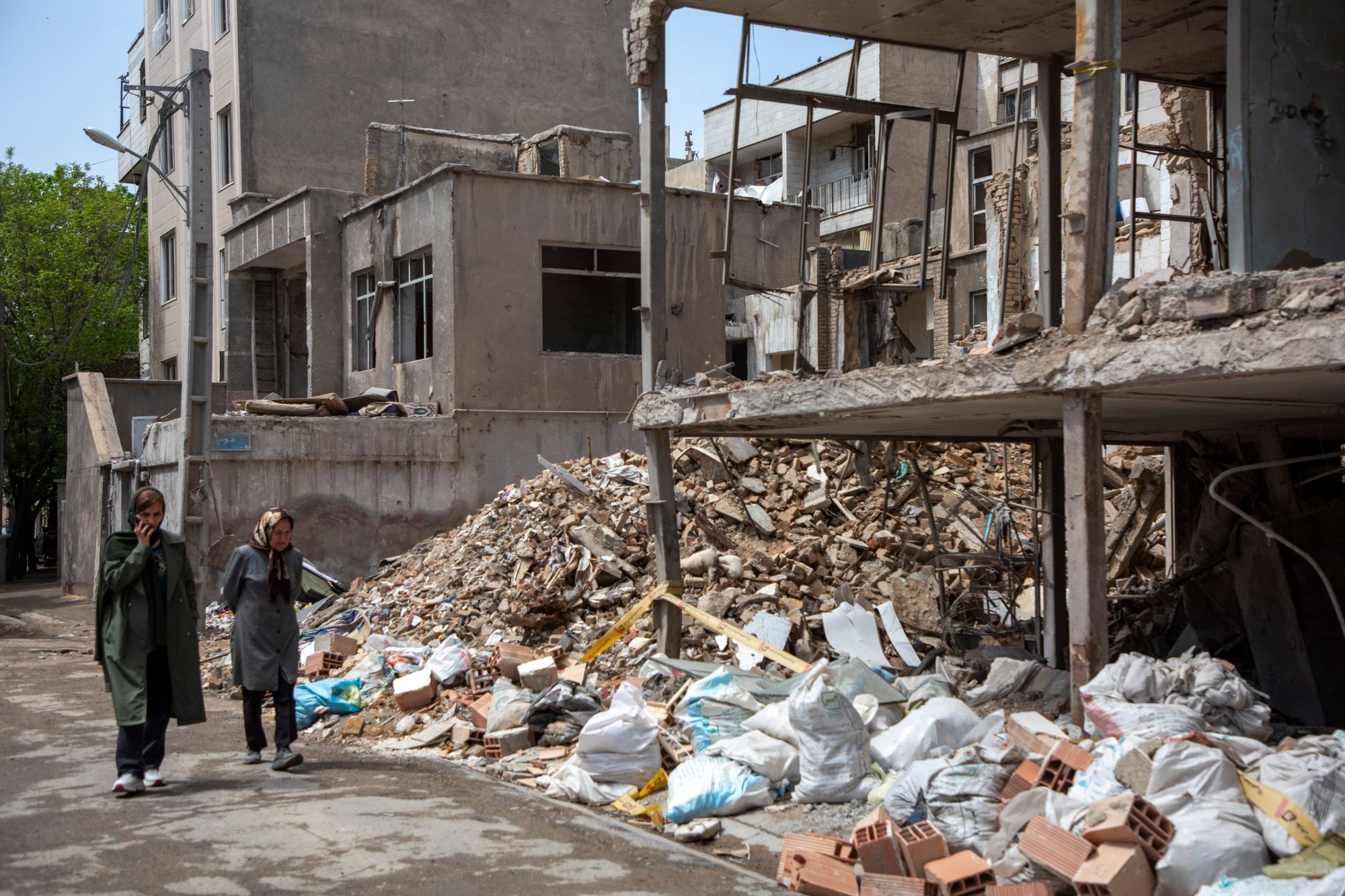Pictured here, people walk past buildings left in ruins by U.S. and Israeli airstrikes in southern Tehran on April 4, 2026