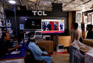 People watch news on a television screen at a shop in Hyderabad