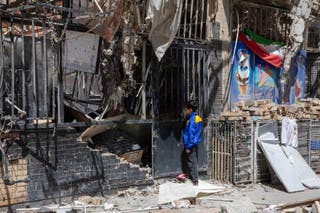 A boy peers into a damaged residential building that, according to Iranian authorities, was hit by a strike on March 4 during the U.S.-Israeli military campaign, on April 14, 2026 in Tehran, Iran.