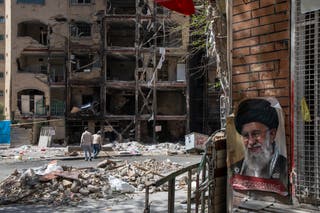 Men walk past a damaged residential building that, according to Iranian authorities, was hit by a strike on March 4 during the U.S.-Israeli military campaign on April 14, 2026 in southeastern Tehran, Iran