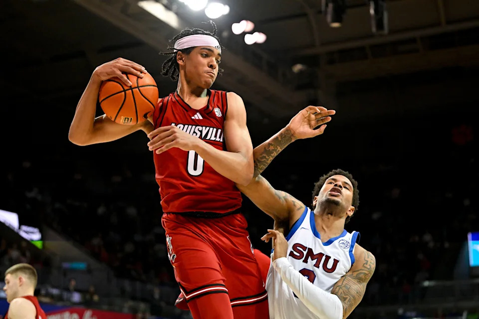 Feb 17, 2026; Dallas, Texas, USA; Louisville Cardinals guard Mikel Brown Jr. (0) grabs a rebound in front of SMU Mustangs forward Corey Washington (3) during the second half at Moody Coliseum. Mandatory Credit: Jerome Miron-Imagn Images